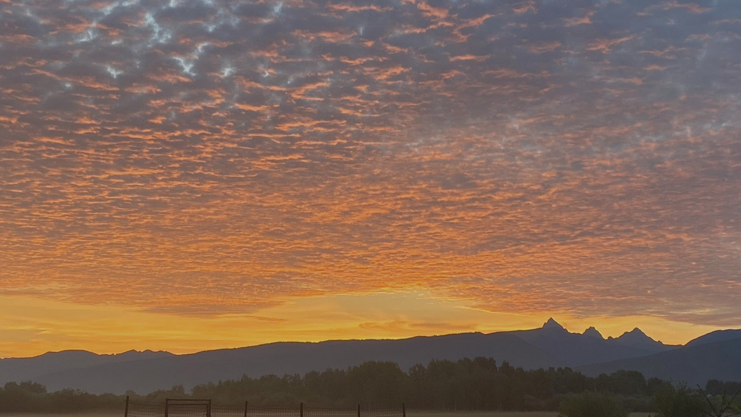 Sunrise over the Teton range under a rippled orange sky