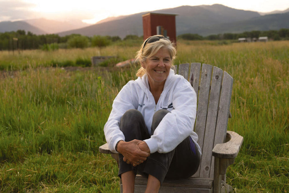 Sandy Hessler sitting in an Adirondack chair in the meadow at sunset