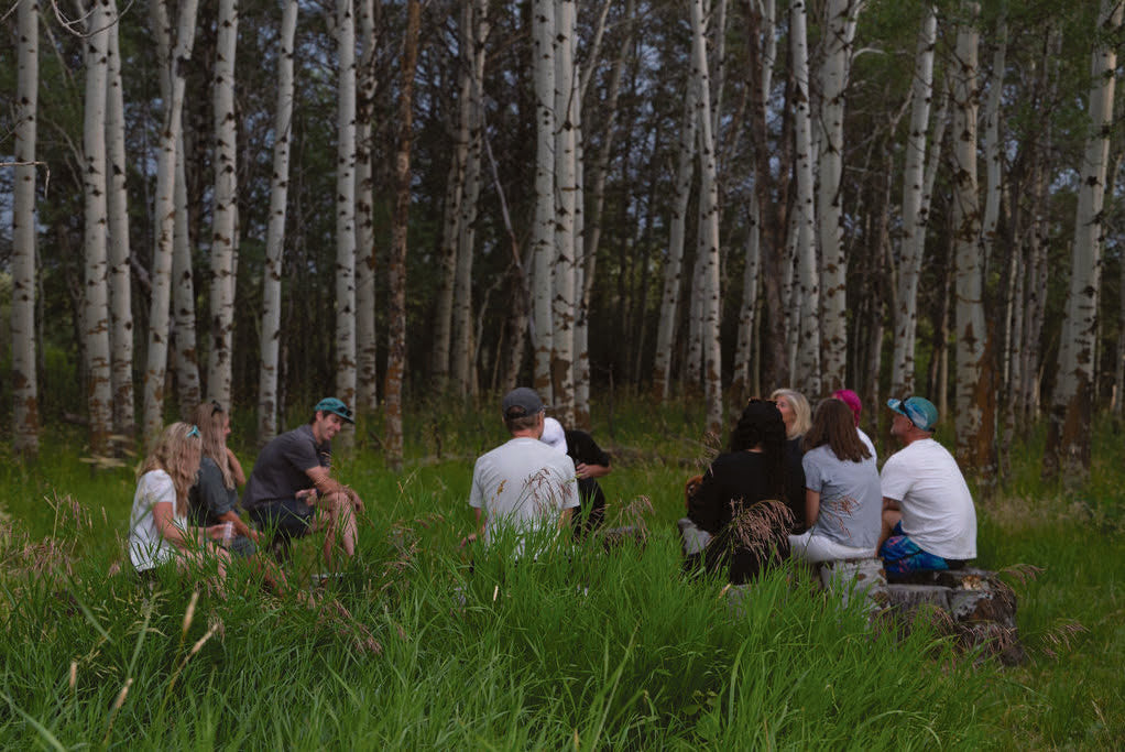 A group gathered in a circle in the aspen grove during an ARC session