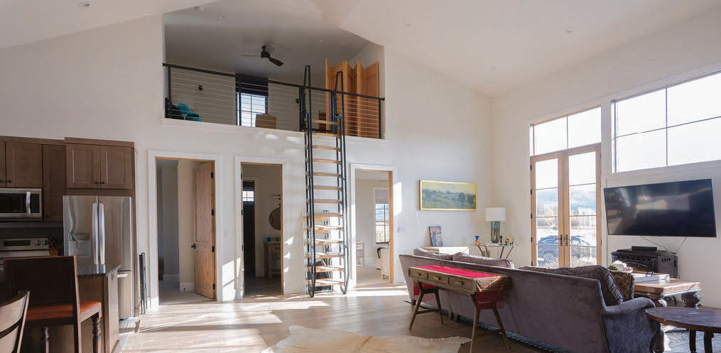 The guest house living area with a cowhide rug, writing desk, and stairs to the loft