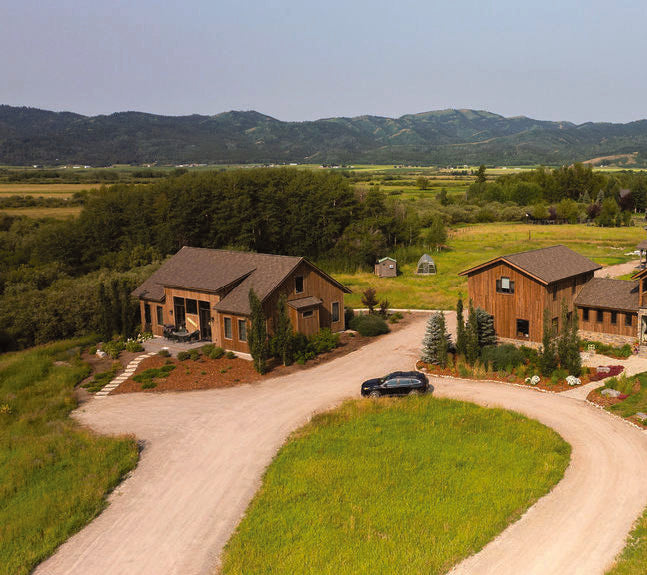 Aerial view of the Dragonfly Lane farmhouse and outbuildings with the gravel drive curving through the meadow