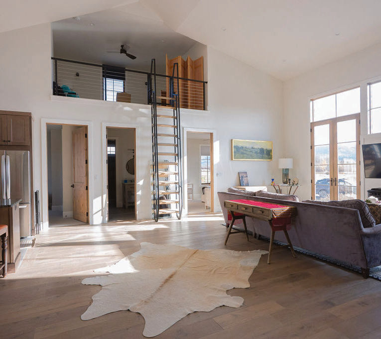 The guest house living room with a lofted sleeping area and windows onto the meadow