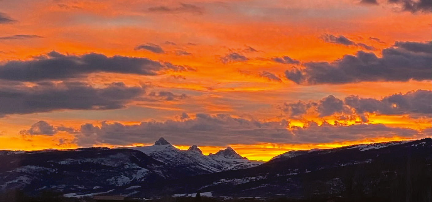 A blazing orange sunset over the silhouetted Teton range